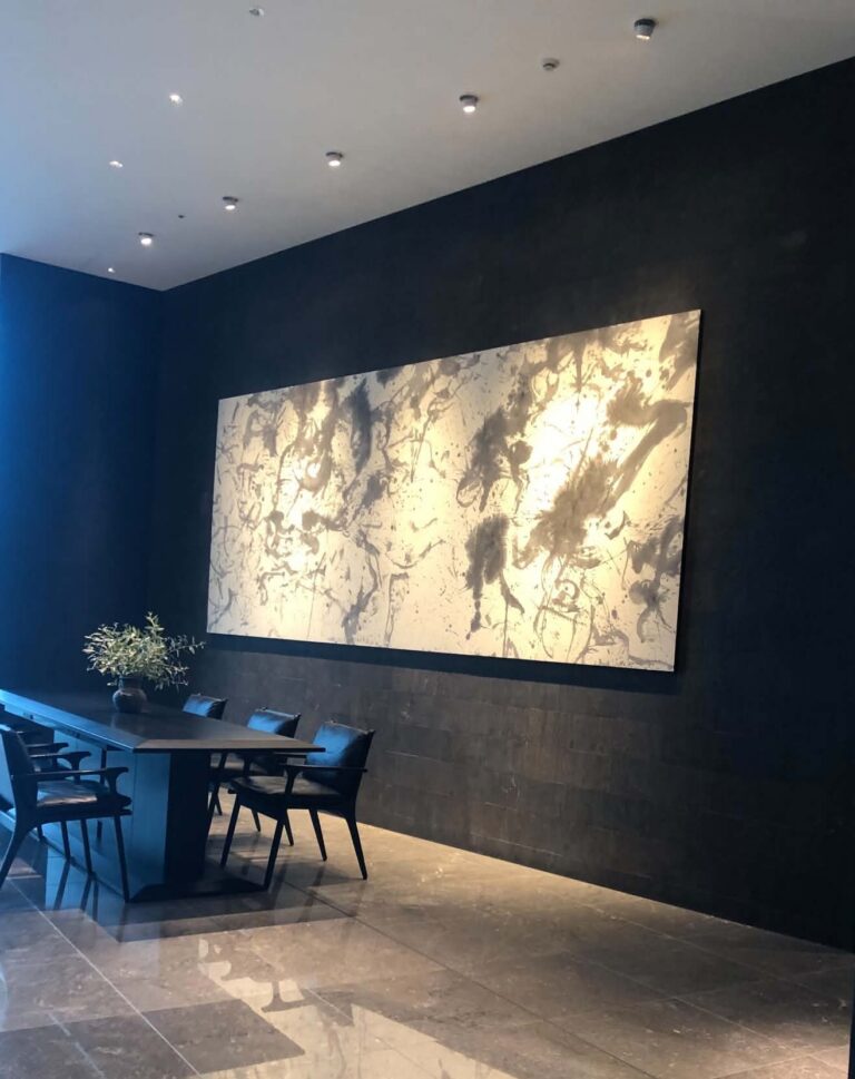 Local Secrets Edition 4: The Penthouse In The Sky. Image of a black and white splattered pain artwork in a large room with marble tiles and a dining table with 6 chairs and vase in the center.